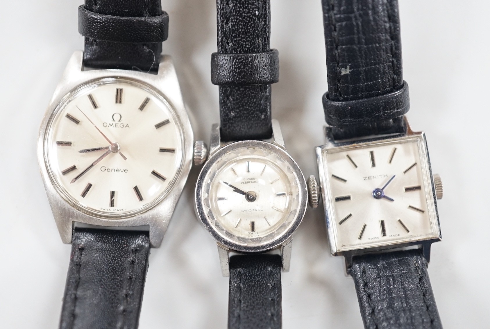 A lady's stainless steel Omega manual wind wrist watch, with baton numerals, together with a lady's stainless steel Zenith square dial manual wind wrist watch and a similar Girard Perregaux manual wind wrist watch.